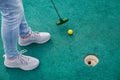 Woman playing mini golf and trying putting ball into hole Royalty Free Stock Photo