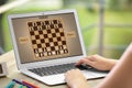 Woman playing online chess on laptop at table, closeup