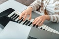 Woman playing piano record music on synthesizer using notes and laptop. Female hands musician pianist improves skills playing