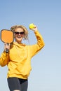 woman playing pickleball game, hitting pickleball yellow ball with paddle, outdoor sport leisure activity.