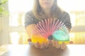 Woman playing with plastic rainbow magic spring to relieve stress while sitting at table at home