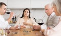 Woman playing poker with husband and elderly parents at home