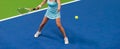 Woman playing tennis on blue floor. Professional sport concept