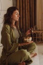 Woman playing on Tibetan singing bowl while sitting on yoga mat. Vintage tonned. Soft focus blurred and noise effect