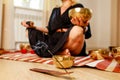 Woman playing on a tibetian singing bowl in cozy room meditating in a yoga Royalty Free Stock Photo