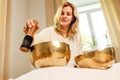 Woman playing on a tibetian singing bowl in cozy room meditating in a yoga Royalty Free Stock Photo