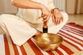 Woman playing on a tibetian singing bowl in cozy room meditating in a yoga Royalty Free Stock Photo