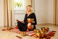 Woman playing on a tibetian singing bowl in cozy room meditating in a yoga Royalty Free Stock Photo