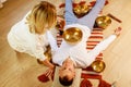 Woman playing on a tibetian singing bowl maling massage meditation for a man Royalty Free Stock Photo