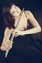 Woman playing transverse flute on black.