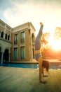 Woman playing yoga hand stand pose beside water pool against beautiful sun light