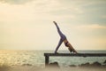Woman playing yoga pose on beach pier with morning light Royalty Free Stock Photo