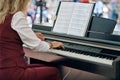 Woman plays electric piano at outdoor music performance, adult female pianist with nimble hands