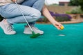 Woman plays mini golf and taking ball out from the hole