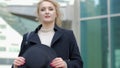 Woman plays with modern black hat moving wide-brimmed chapeau at black coat bottom in street slow motion low angle shot