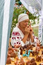 Woman plays music on a clay whistle in the shop with clay Souvenirs and toys at the festival of cheese Adyghe in Adygea