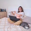 A woman plays a musical instrument for lessons in a laptop. Learning classical music and flute during pregnancy