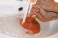 Woman with plunger trying to remove clogged sinks. Royalty Free Stock Photo