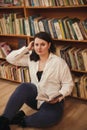 Plus size elegant woman in white shirt in library