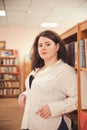 Plus size elegant woman in white shirt in library