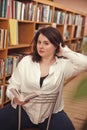 Plus size elegant woman in white shirt in library