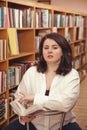 Plus size elegant woman in white shirt in library