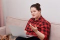 Woman plus size model working online with laptop on her lap, next to a pet dog. Royalty Free Stock Photo