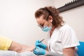 Woman podiatrist in blue gloves does a caring procedure for the client& x27;s nails. The concept of podology and