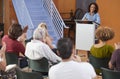 Woman At Podium Chairing Neighborhood Meeting In Community Centre Royalty Free Stock Photo