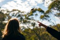 woman pointing at a bird in the distant treetops