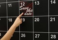 Woman pointing on board calendar with phrase SAVE THE DATE Royalty Free Stock Photo