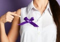Woman pointing finger on purple ribbons on a purple background. World epilepsy day Royalty Free Stock Photo