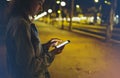 Woman pointing finger on screen smartphone on background illumination bokeh light in night atmospheric city, hipster using in hand Royalty Free Stock Photo