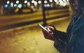Woman pointing finger on screen smartphone on background illumination bokeh light in night atmospheric city, hipster using in hand Royalty Free Stock Photo