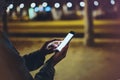 Woman pointing finger on screen smartphone on background illumination bokeh light in night atmospheric city, hipster using in hand Royalty Free Stock Photo