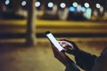 Woman pointing finger on screen smartphone on background illumination bokeh light in night atmospheric city, hipster using in hand Royalty Free Stock Photo