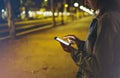 Woman pointing finger on screen smartphone on background illumination bokeh light in night atmospheric city, hipster using in hand Royalty Free Stock Photo