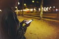 Woman pointing finger on screen smartphone on background illumination bokeh light in night atmospheric city, hipster using in hand Royalty Free Stock Photo