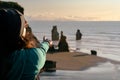 Woman pointing with her finger at big rock formations by the beach. Selective focus