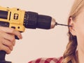 Woman pointing at her head with drill
