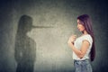 Woman pointing at herself looking at a shadow with long nose of a liar Royalty Free Stock Photo
