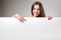 Woman pointing on white billboard over grey Royalty Free Stock Photo