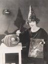 Woman in pointy hat painting a jack o'lantern