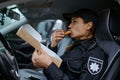 Woman police officer eating donut in car Royalty Free Stock Photo