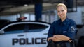 Woman police officer smiling, standing near patrol car with crossed hands, law Royalty Free Stock Photo