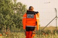 Woman a polish ambulance worker standing back in medical orange uniform with inscription Emergency medical Services.