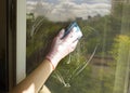 A woman polishing glass using a cleaning sponge and rubber gloves cleaning a window.the girl is cleaning the house