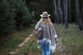 Woman with poncho, cowboy hat and backpack walking in woodland Royalty Free Stock Photo