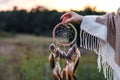 Woman with poncho holding dreamcatcher during sunrise