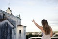 A woman on the porch with her back to the camera pointing to the cross against the sky and church in the background Royalty Free Stock Photo